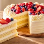 Hausgemachter Geburtstagskuchen mit luftigem Vanille-Biskuit, cremiger Vanille-Sahnefüllung und frischen Beeren.